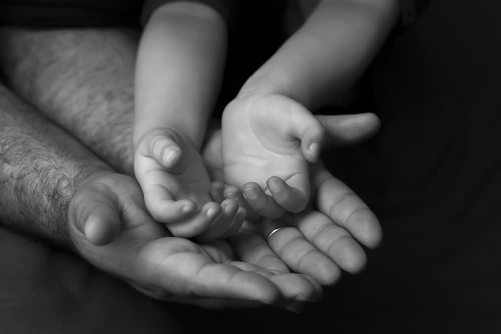A child's hands resting in a parent's palms