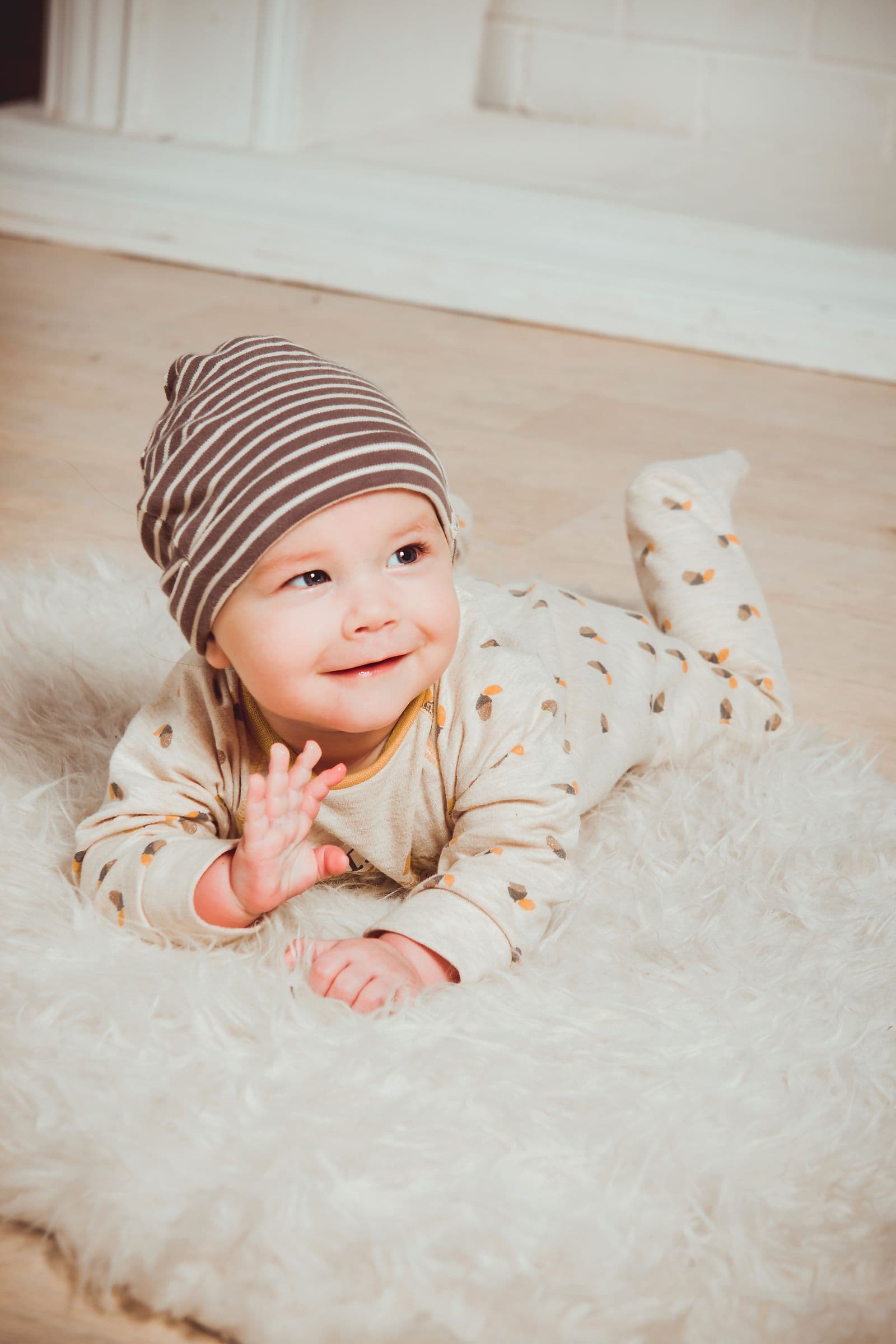A smiling baby lying on a soft rug